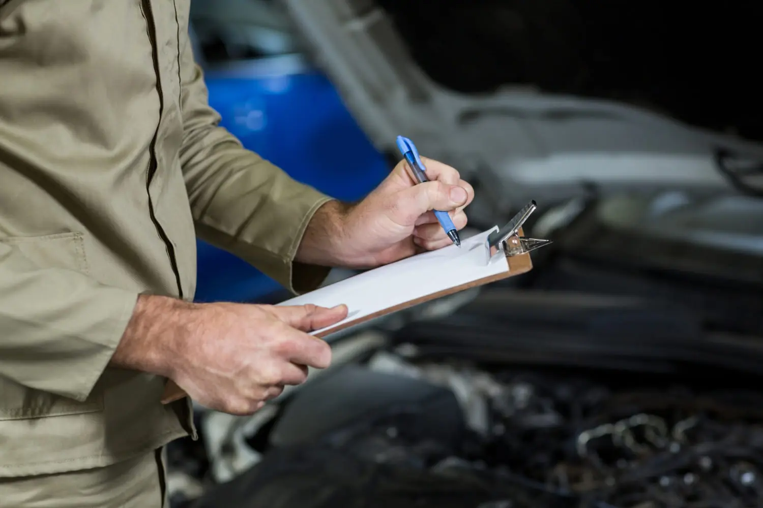 Mechanic inspecting a car to check what an extended warranty covers and excludes