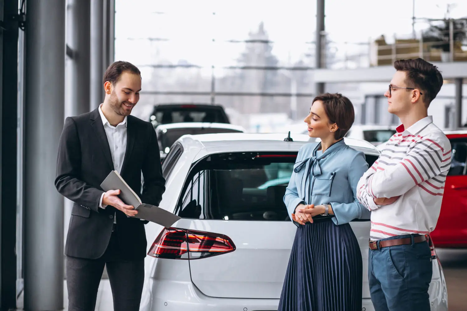 Car buyers at a dealership weighing total cost of ownership beyond sticker price